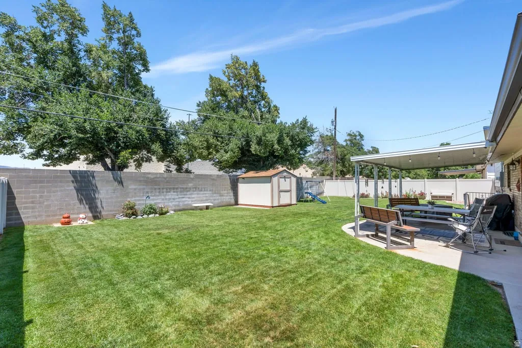 Expansive green lawn with a covered patio area featuring an awning structure and string lighting