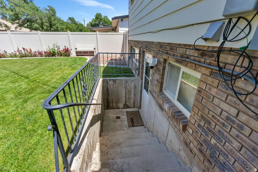 Exterior access to lower level featuring concrete steps with a wrought iron railing