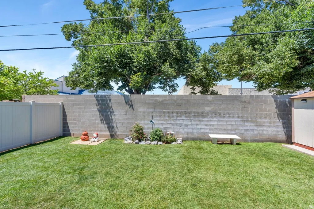 Manicured lawn with a concrete block privacy wall and a white vinyl fence