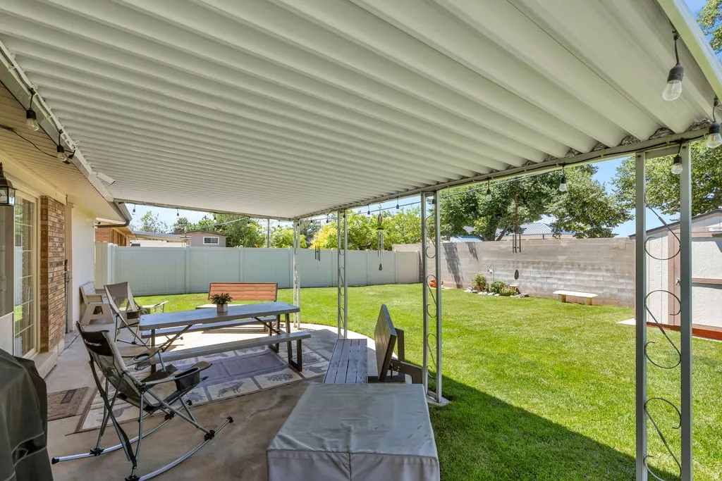 Covered patio featuring corrugated roofing, string lighting, concrete flooring, and direct access to a grassy yard