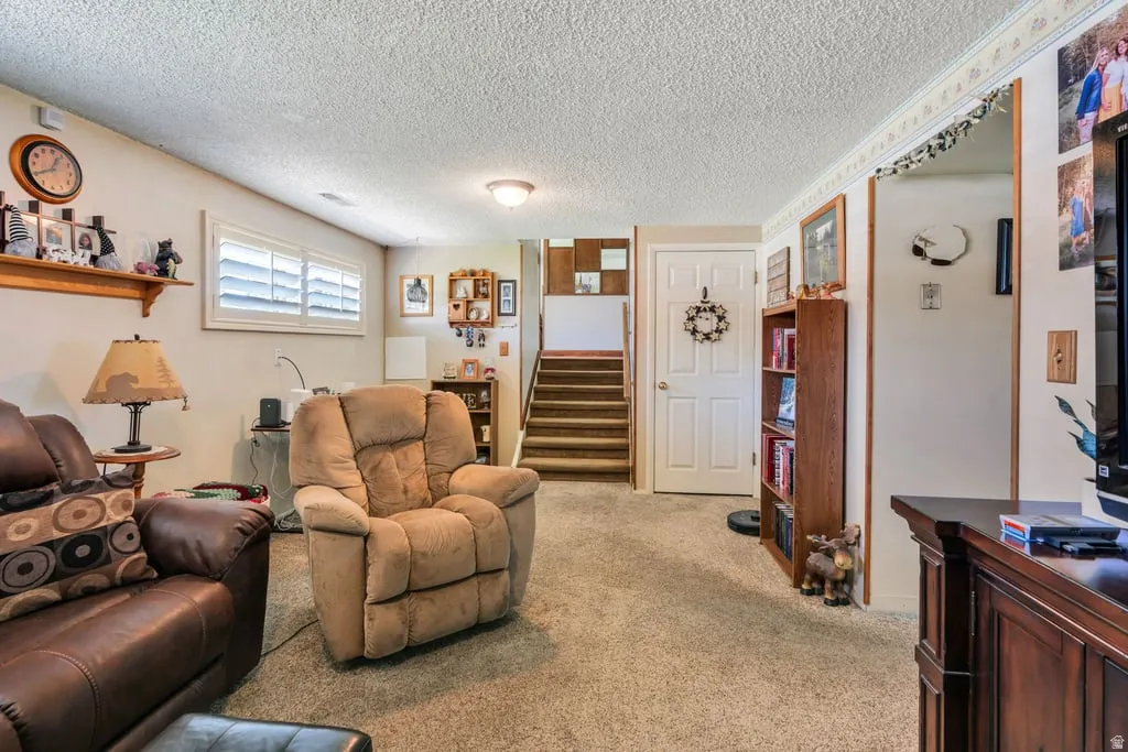 Carpeted room featuring dual windows with plantation shutters, a white paneled door, and a staircase with wood-finish risers