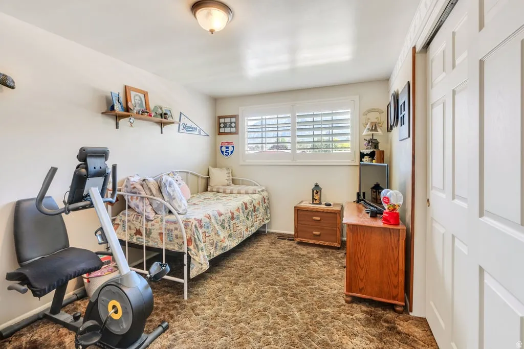 Interior room featuring a window with plantation shutters, a ceiling-mounted light fixture, and a built-in sliding closet door