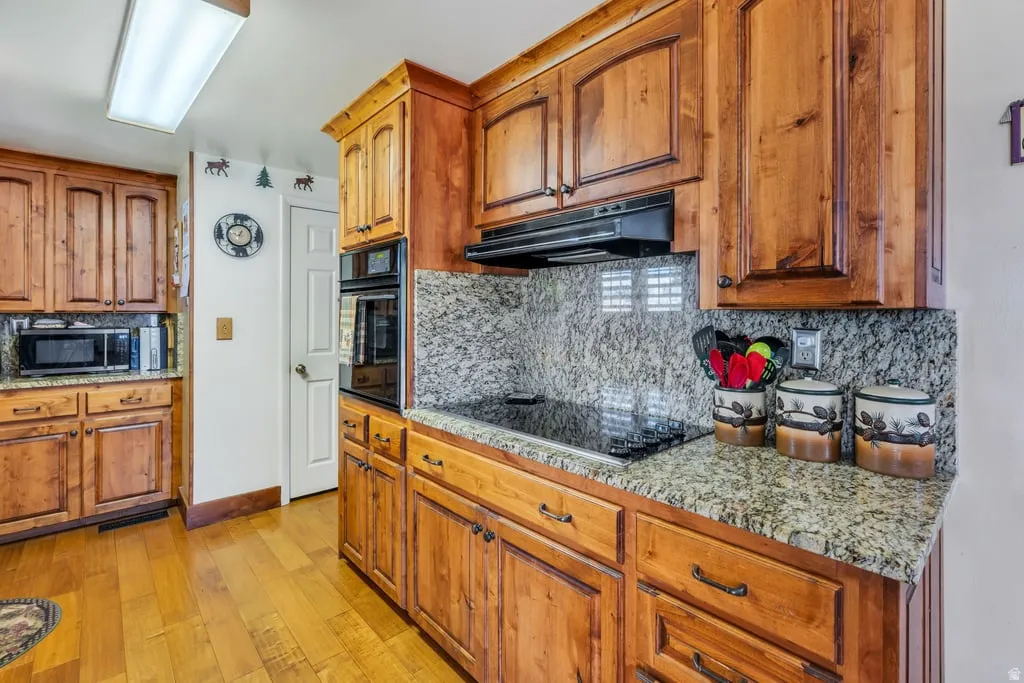 Kitchen featuring wood cabinetry, granite countertops, and a smooth cooktop