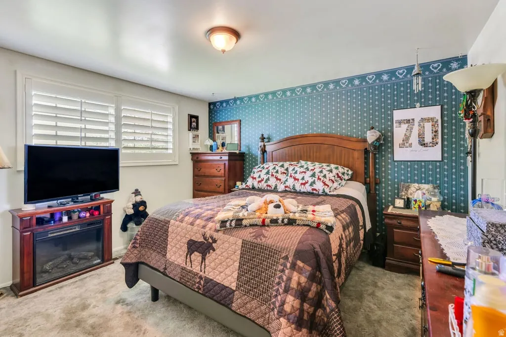 Master bedroom featuring a decorative accent wall, a wood-finish bed frame, and white plantation shutters