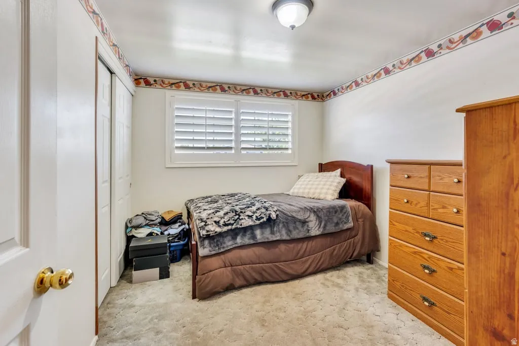 Room featuring a window with white louvered shutters, carpeted flooring, and a ceiling-mounted light fixture