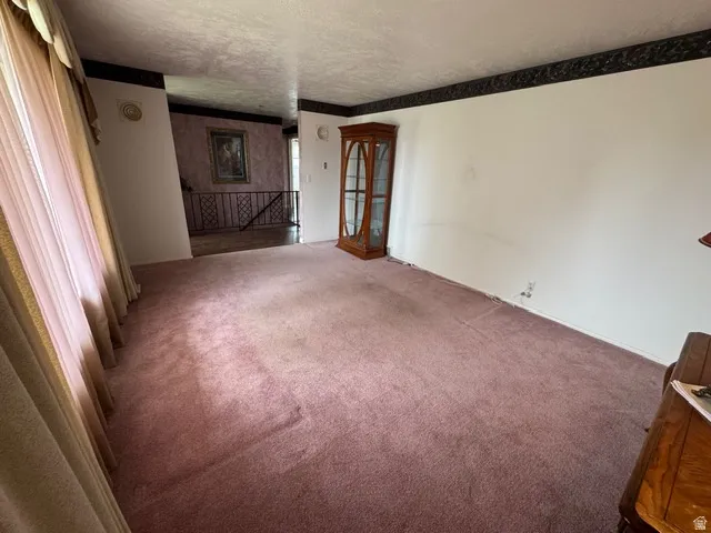 Carpeted formal living room featuring a textured ceiling and plenty of natural light