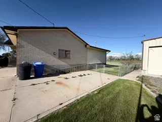 Brick exterior with a sheltered entry, concrete patio, and fenced grass area