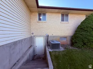 Exterior featuring a secondary entry with concrete stairs, light-colored brick, horizontal siding, and a mature evergreen shrub
