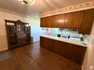 Wood-finish flooring throughout, featuring a kitchen peninsula with wood cabinetry and a light-colored countertop