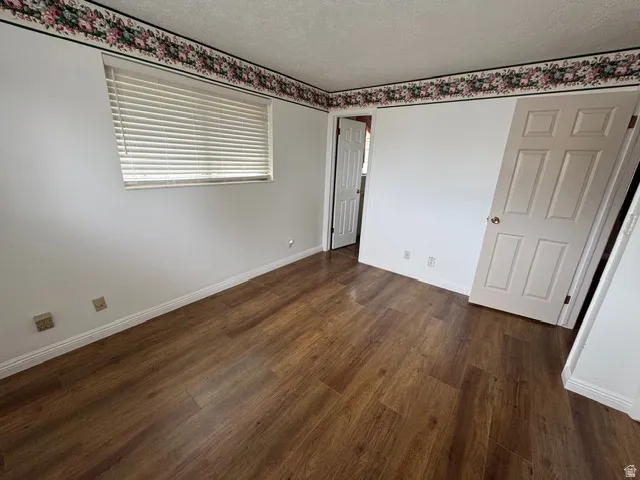 Unfurnished bedroom with a textured ceiling and dark wood-style laminate floors