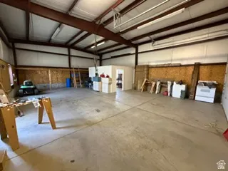 Spacious industrial interior featuring a concrete floor, exposed steel beams, and high ceilings with fluorescent lighting