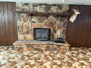 Stone-clad fireplace with a hearth, featuring a wood-burning stove insert