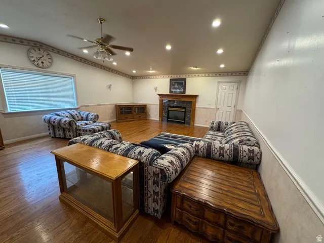 Living room featuring wood finished floors, a tile fireplace, vaulted ceiling, recessed lighting, and a ceiling fan