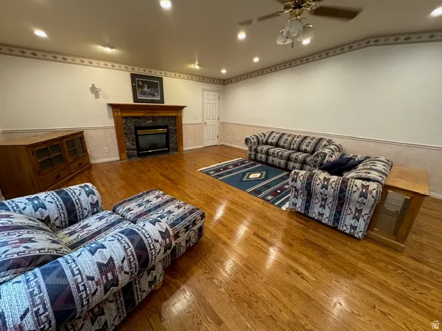 Living room with hardwood flooring, ceiling fan, a high end fireplace, and recessed lighting