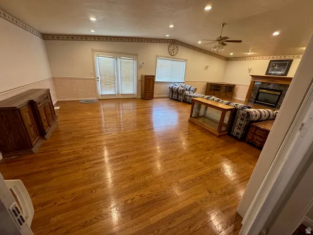 Living area featuring a high end fireplace, wood finished floors, vaulted ceiling, and a ceiling fan