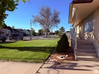 Exterior featuring a front porch with railing, concrete steps, and a neatly manicured lawn