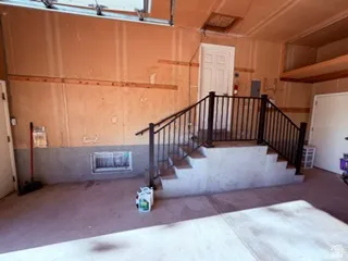 Concrete garage flooring with a built-in staircase featuring a black metal railing
