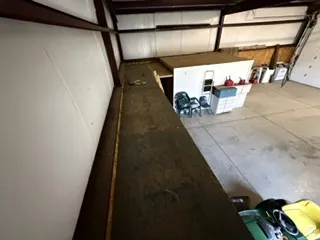 Industrial space featuring an expansive concrete floor, visible metal beam construction, and a mezzanine level
