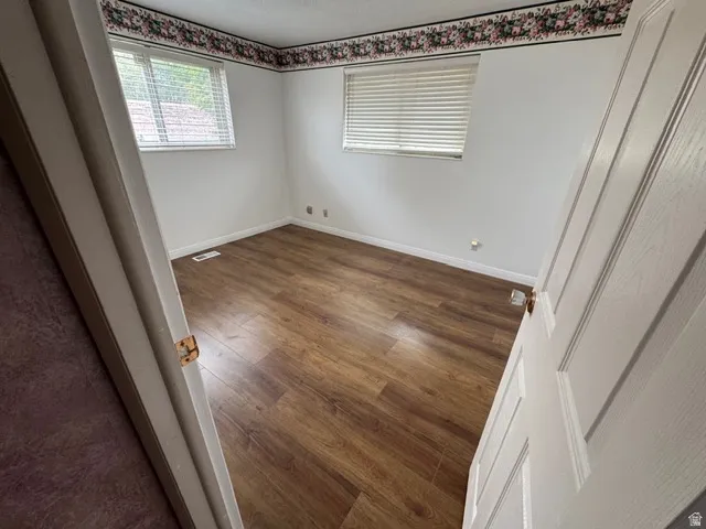 Unfurnished bedroom with dark wood-style laminate floors and baseboards
