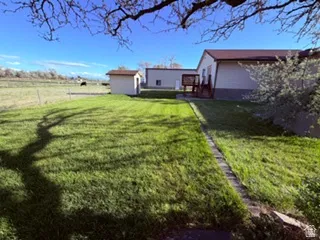 Expansive lawn area featuring a detached storage shed and a raised wooden deck with railings