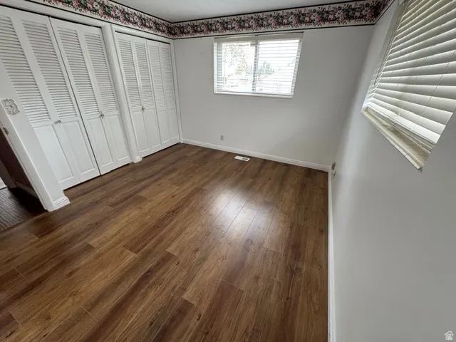 Unfurnished bedroom with multiple closets and dark wood finished floors