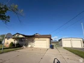 Property exterior featuring a tan facade, attached double-car garage, and a detached garage/shop