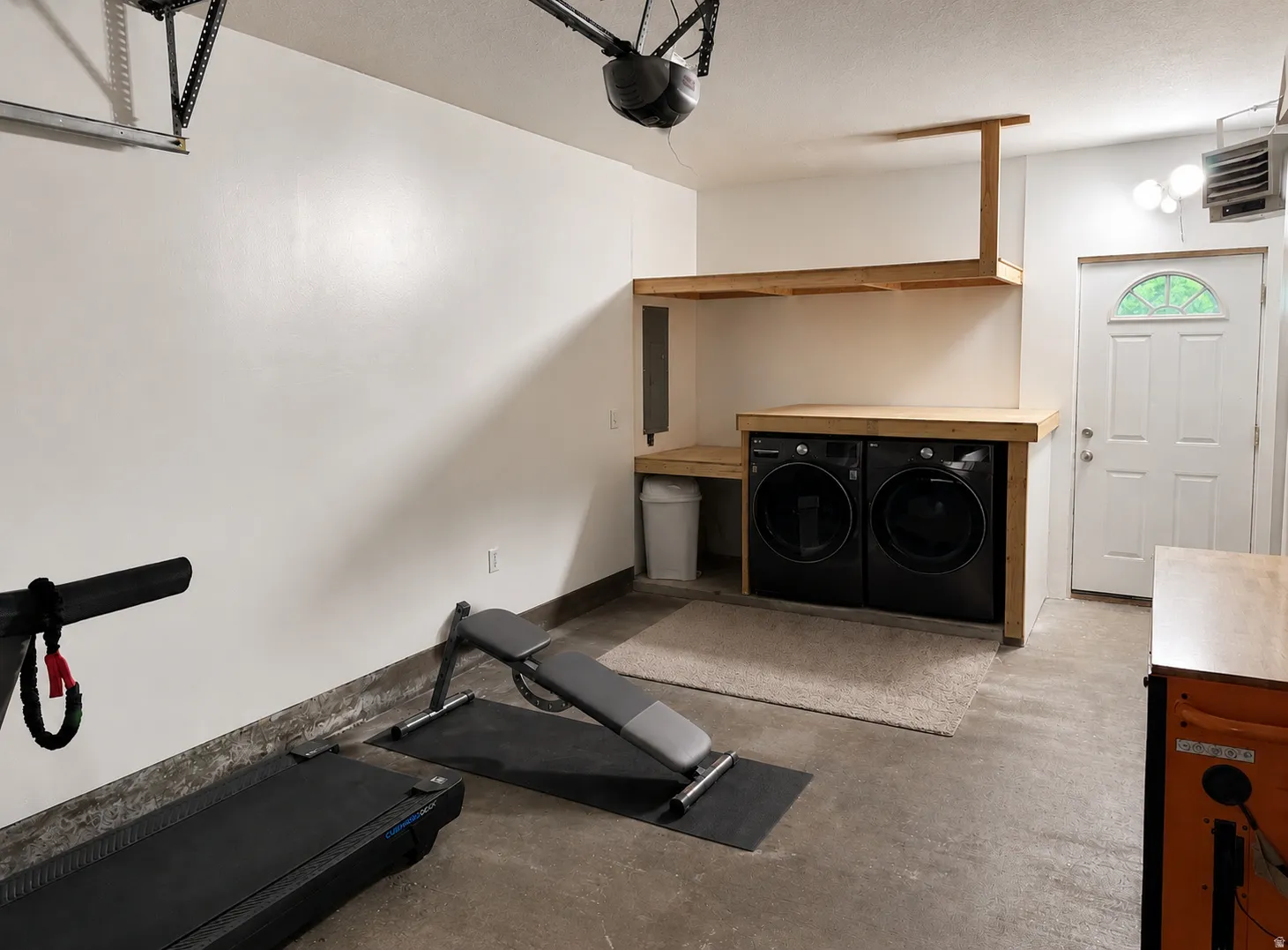 Dedicated laundry area featuring a wood-finish countertop and overhead shelving