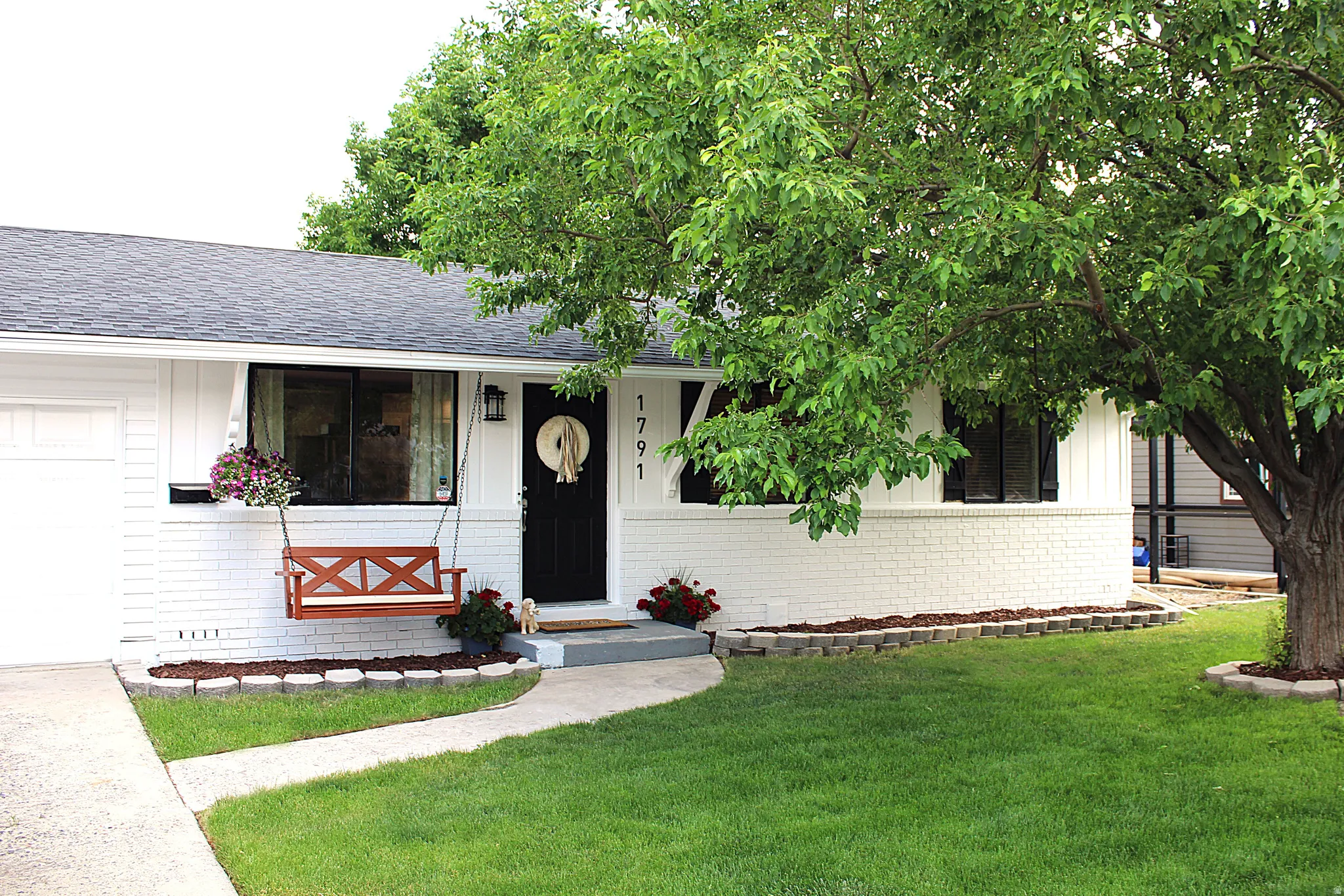 White brick and vertical siding exterior with a dark asphalt shingle roof