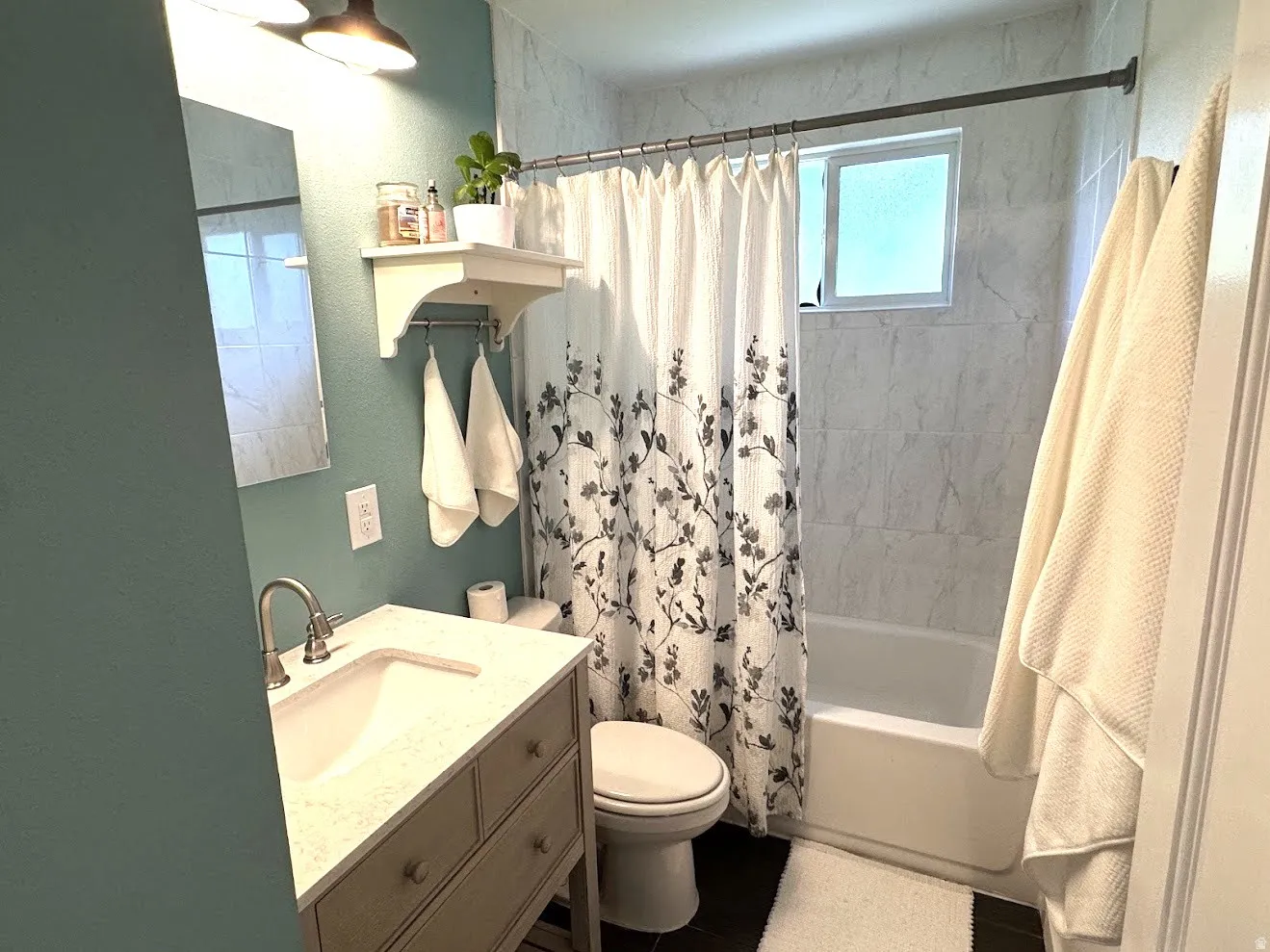 Bathroom featuring a vanity with an integrated sink and light-colored countertop, a toilet, and a combination shower/tub with tile surround