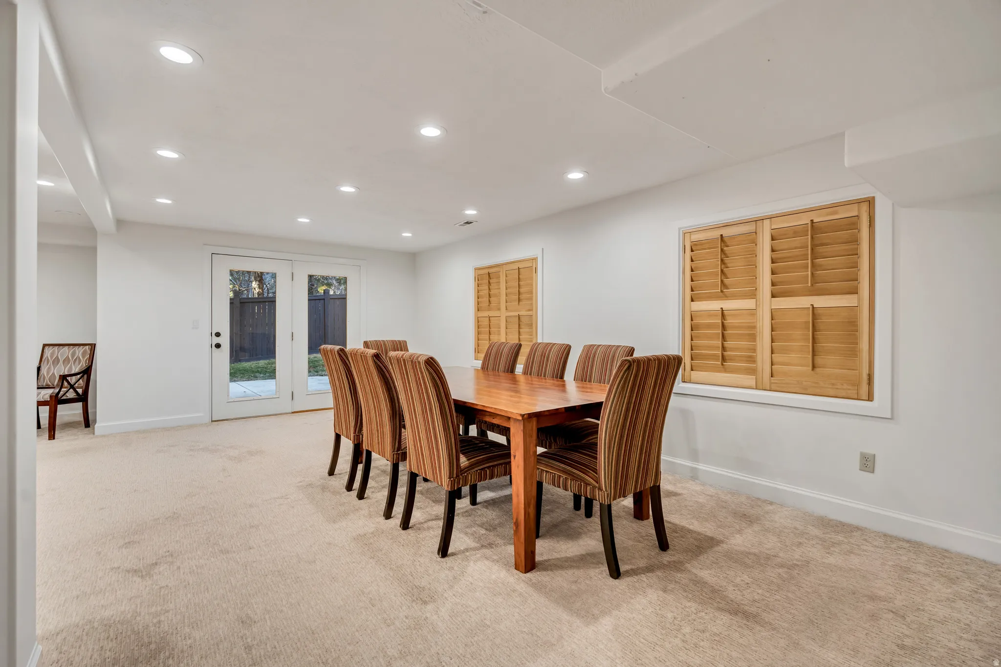 Carpeted room with recessed lighting and double glass-paneled doors