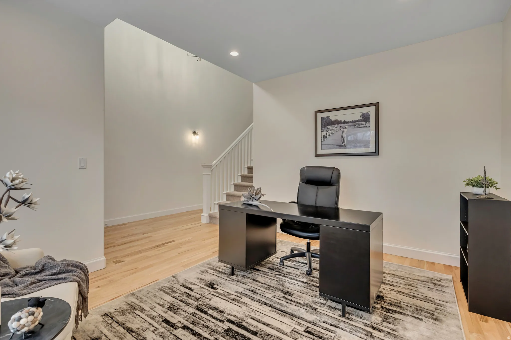Hardwood flooring extends throughout this space, featuring crisp white walls and recessed ceiling lighting