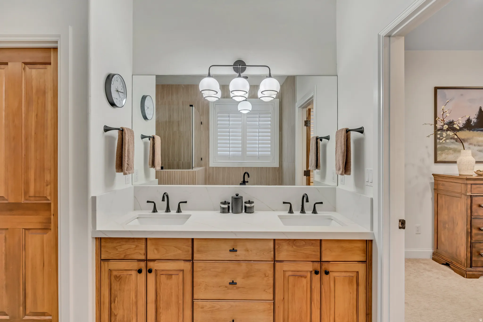 Double vanity featuring wood cabinetry, white countertops, and matte black fixtures