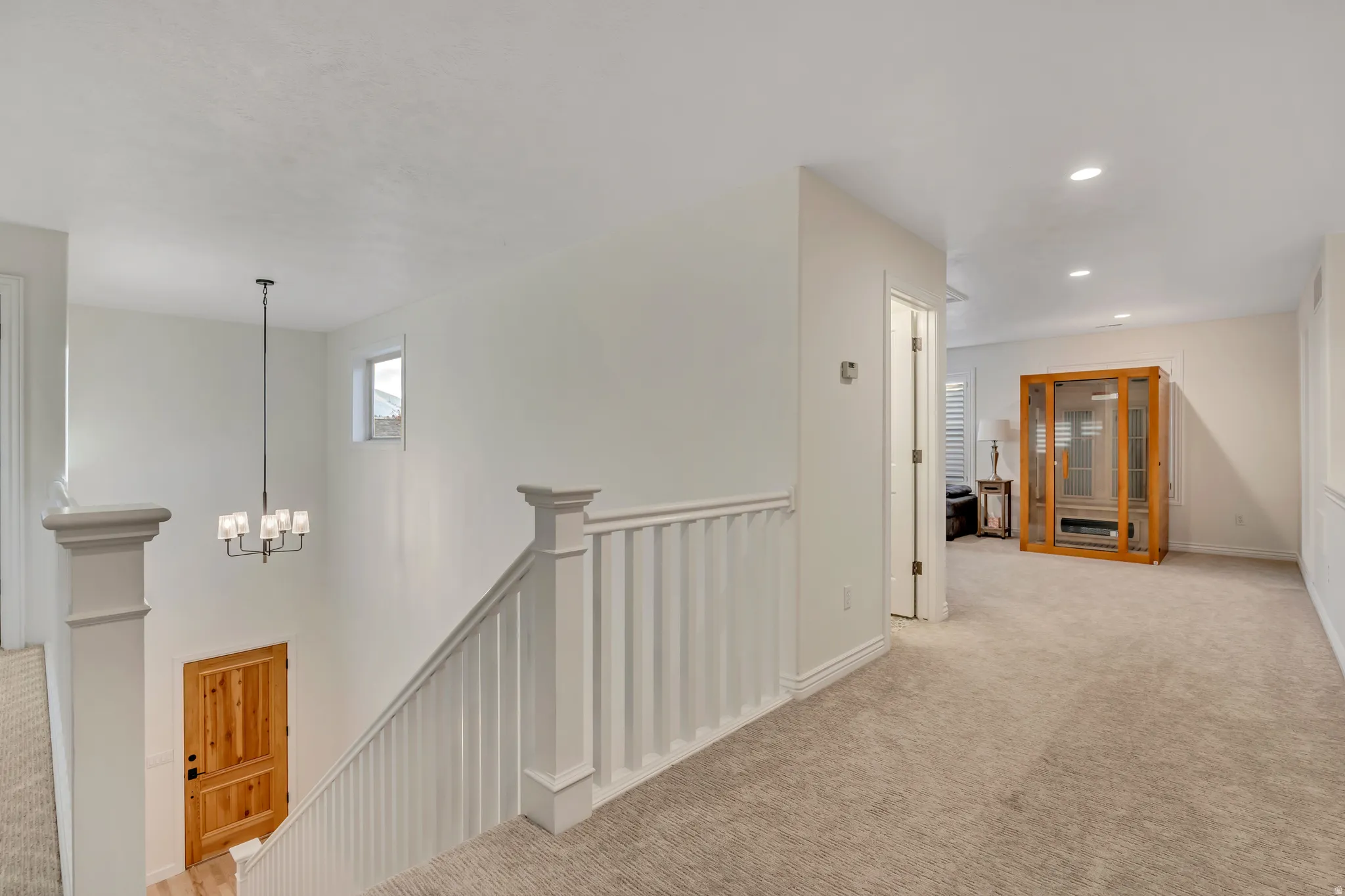 Upper landing with neutral carpet, white balustrade, and recessed lighting