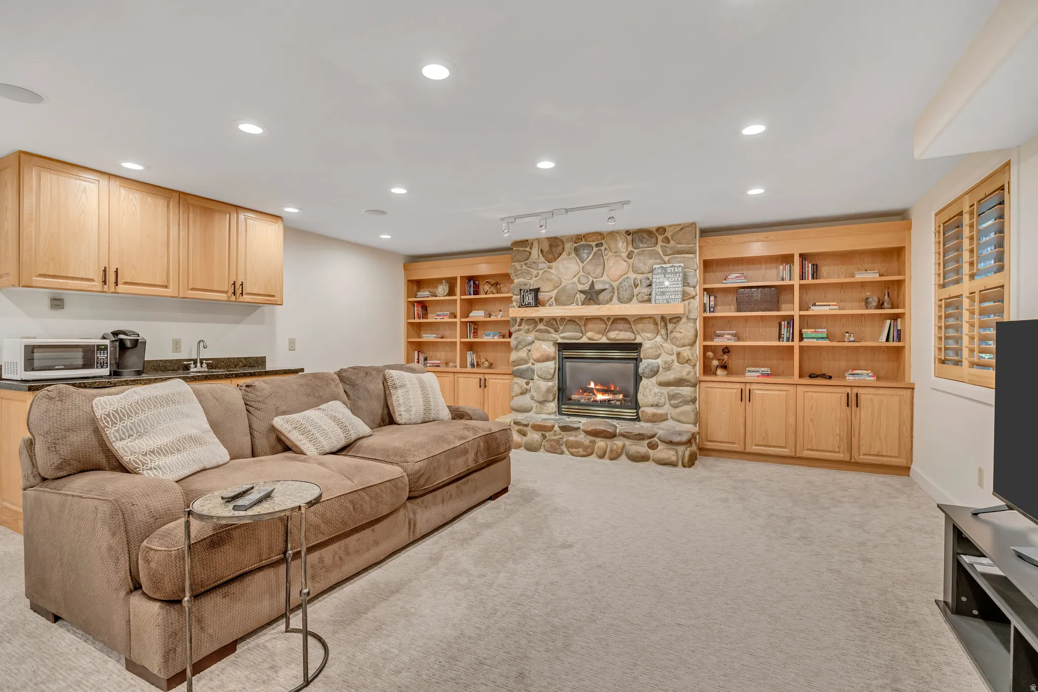 Stone-faced fireplace with a wood mantel, flanked by built-in wood shelving and cabinetry