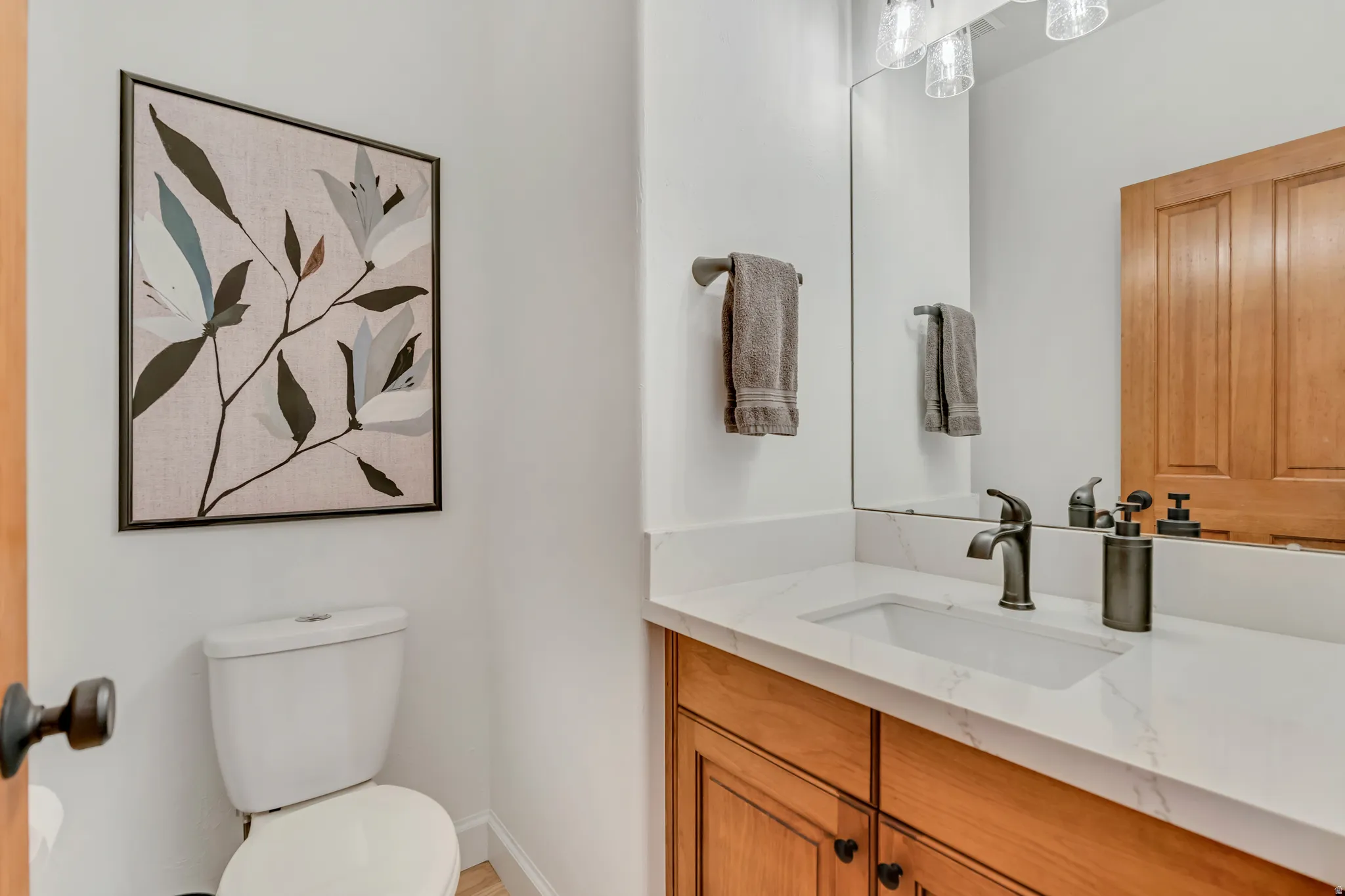 Bathroom vanity featuring a rectangular undermount sink set in a light-toned countertop, complemented by a bronze-finish faucet