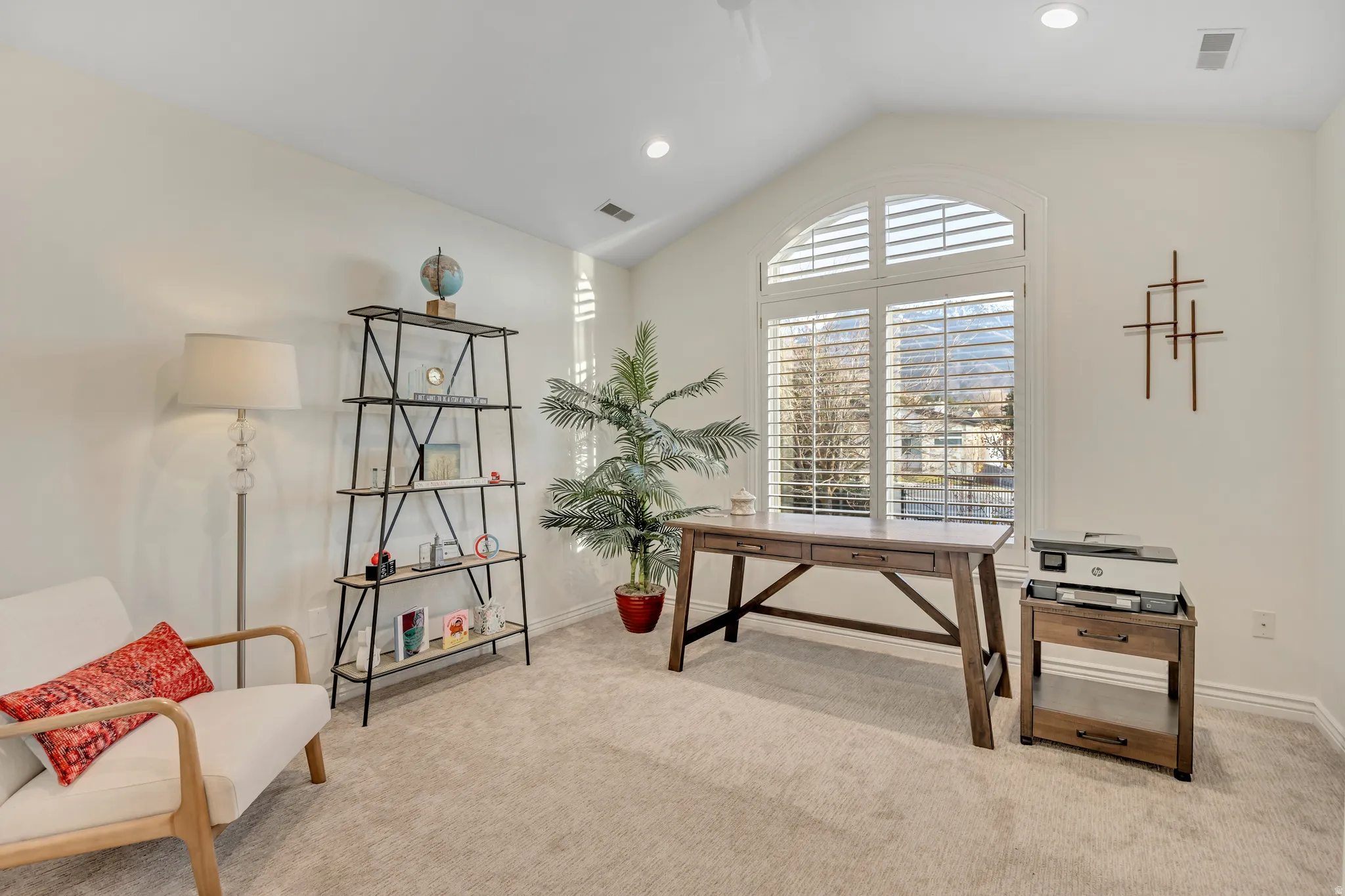 Vaulted ceiling room featuring a large arched window with interior shutters, recessed lighting, and light-toned carpeting