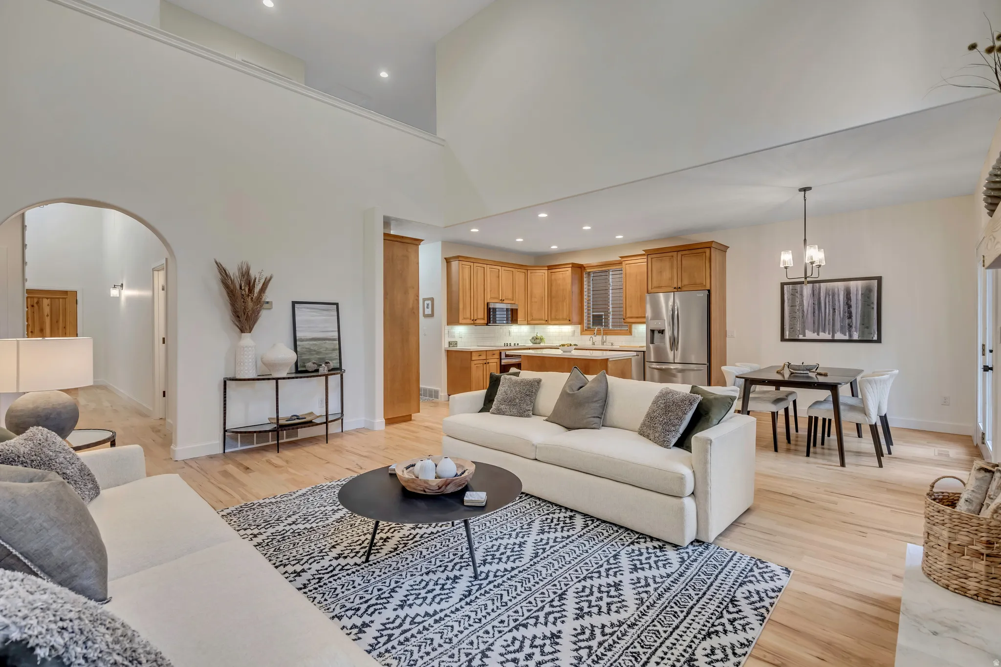 Open-concept living area with light wood-finish flooring, a vaulted ceiling, recessed lighting, and an upper-level overlook