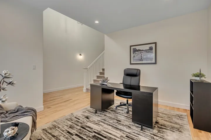 Hardwood flooring extends throughout this space, featuring crisp white walls and recessed ceiling lighting