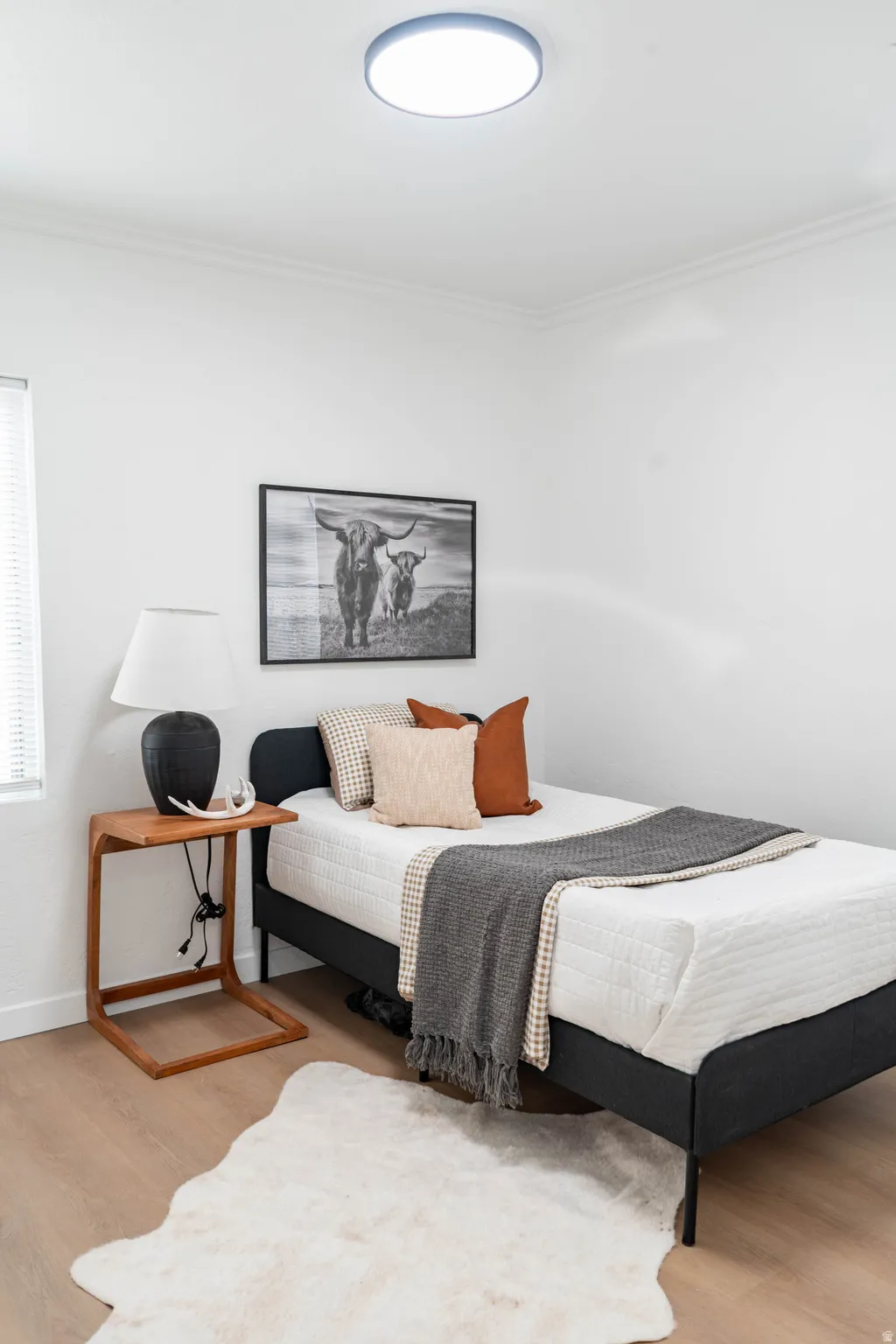Light wood-finish flooring complements white walls with crown molding