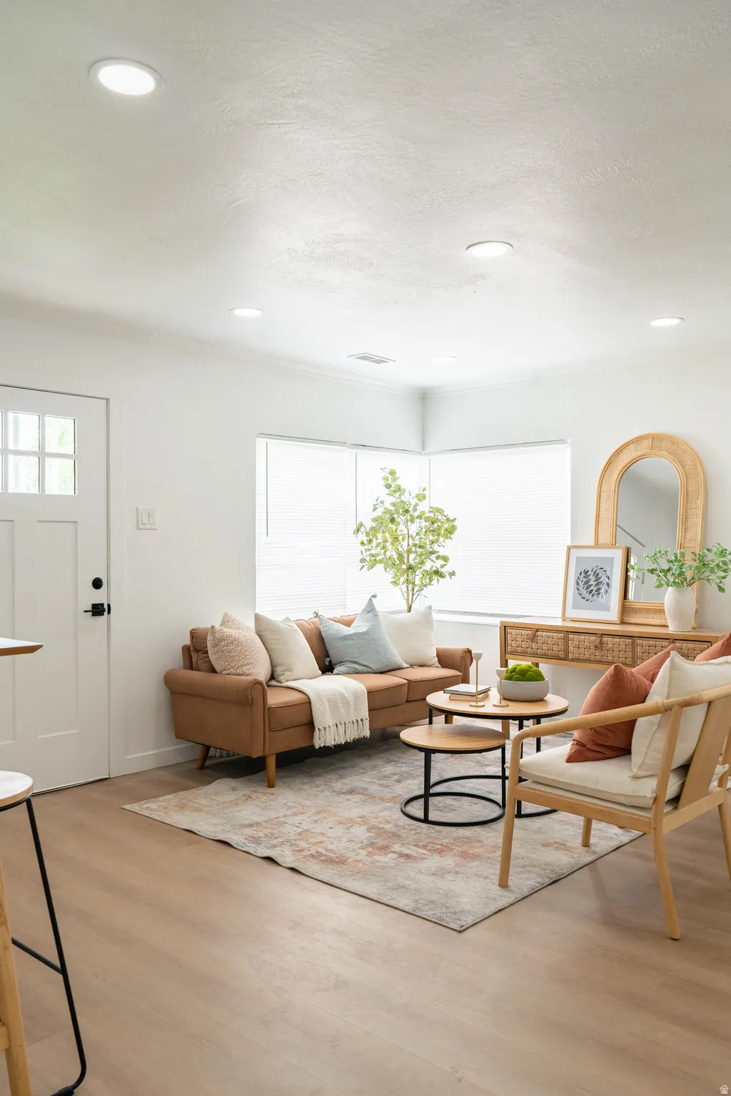 Open-concept living space with light wood-finish flooring, recessed lighting, white walls, and bright window treatments