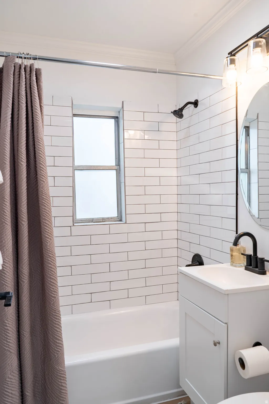Bathroom featuring white subway tile surround, white bathtub, and a window with privacy glass