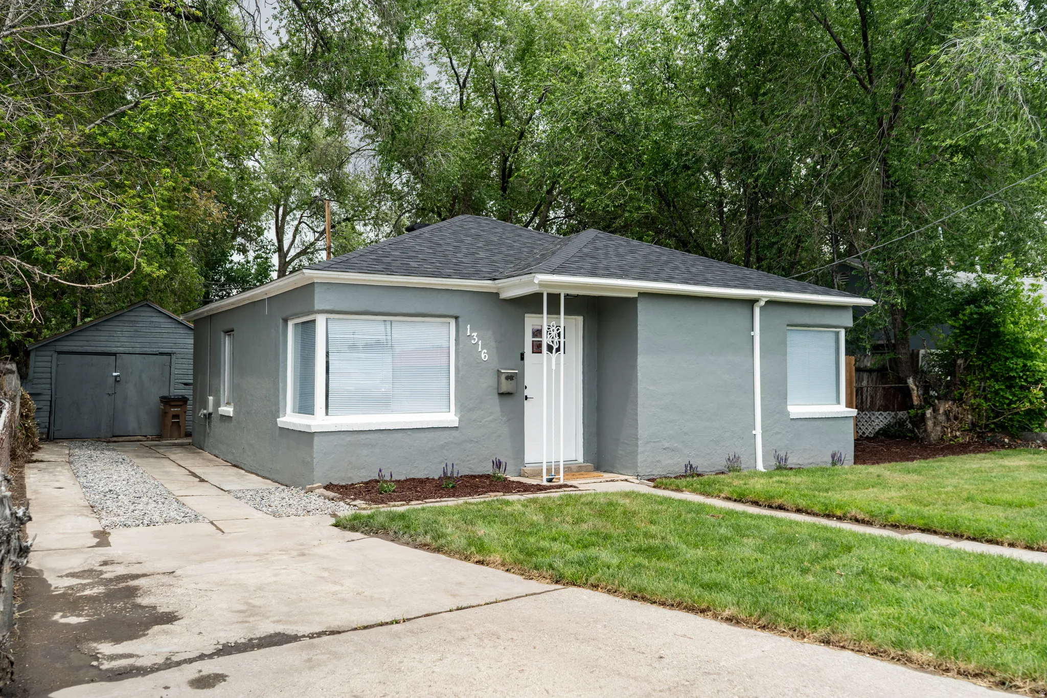 Gray stucco exterior with a dark shingle roof and white trim