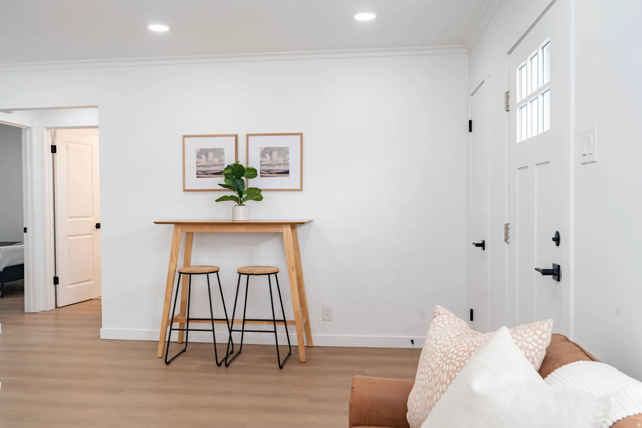 Entryway featuring a white paneled door with windowpanes and black hardware, complemented by light wood-finish flooring, recessed lighting, and crisp white walls