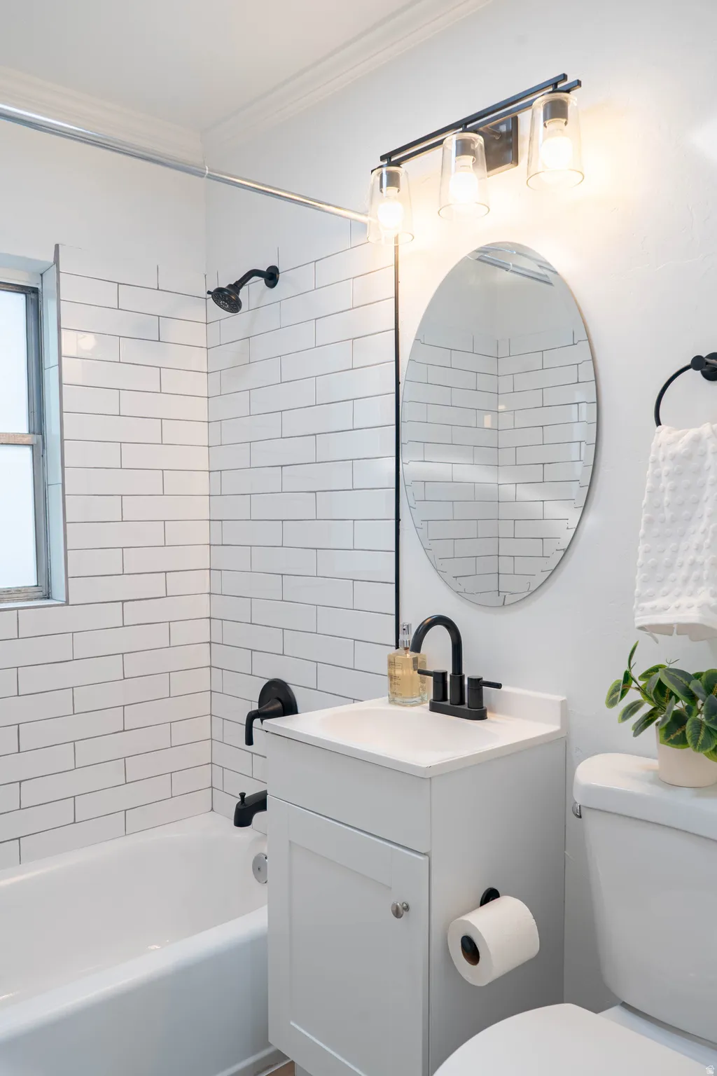 Bathroom featuring a white subway tile surround, white tub, and a vanity with a white countertop