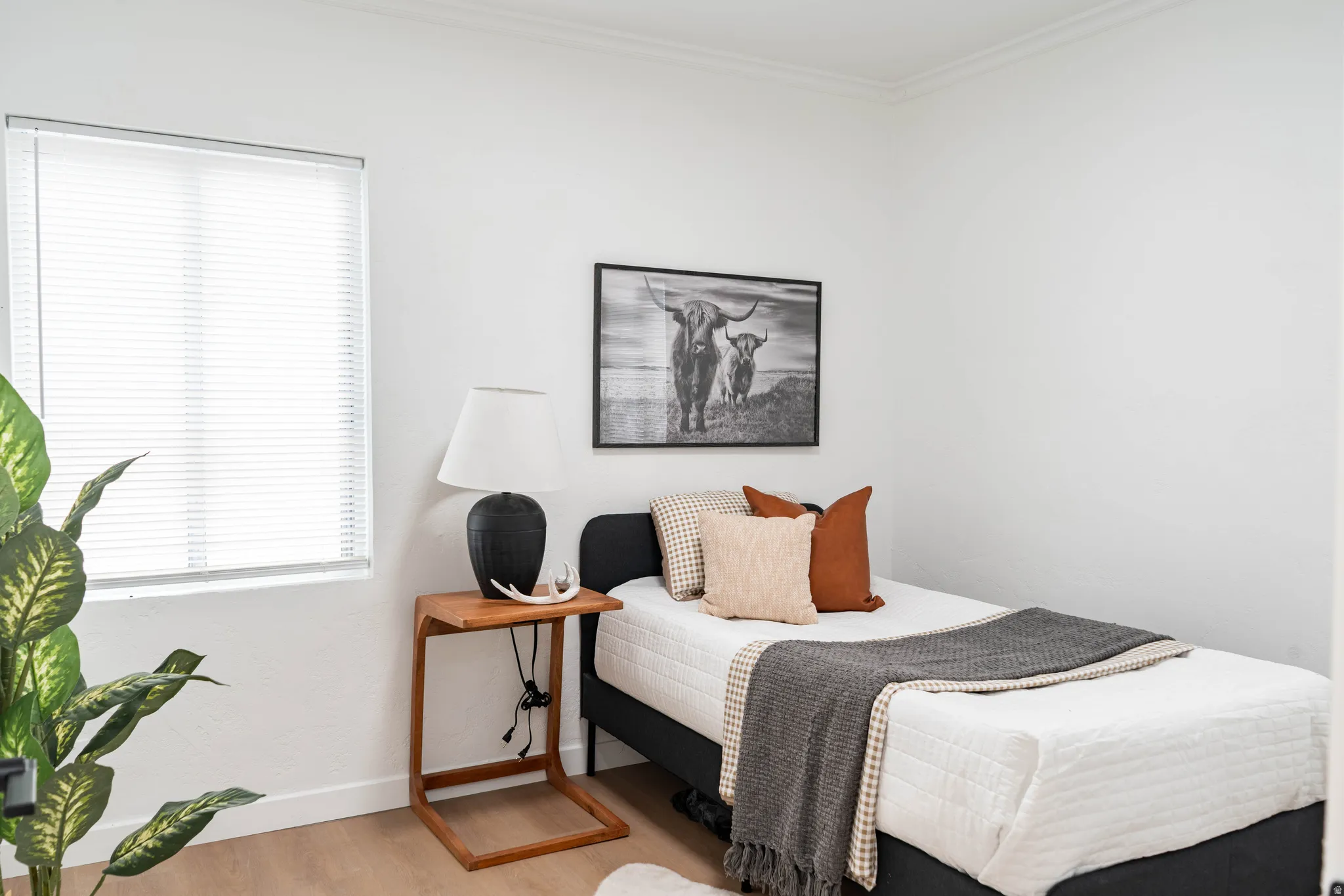 Bright room featuring wood-finish flooring, white walls, and a window with blinds
