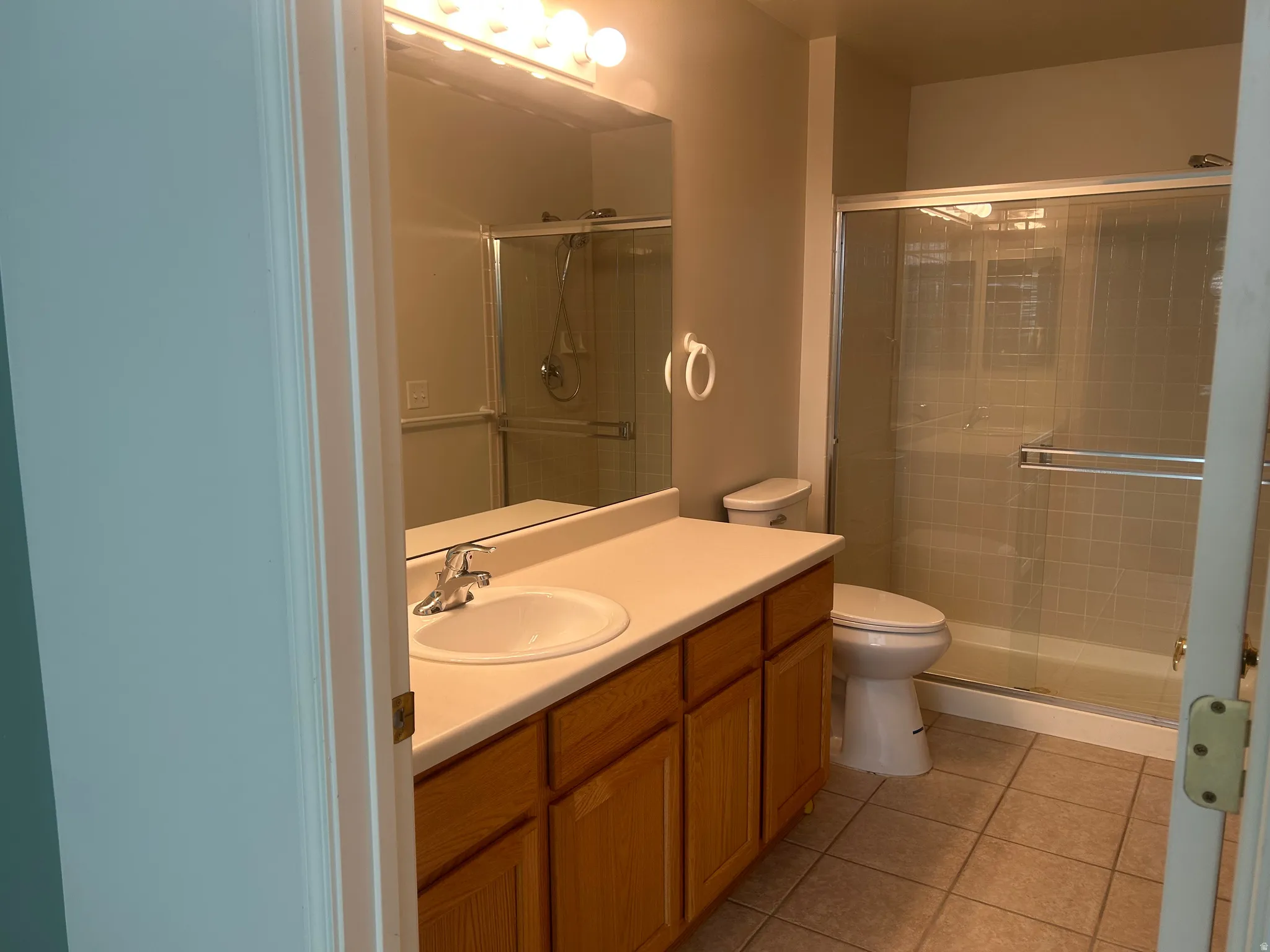 Bathroom featuring a vanity with wood-finish cabinetry, an integrated sink, and a light-toned countertop