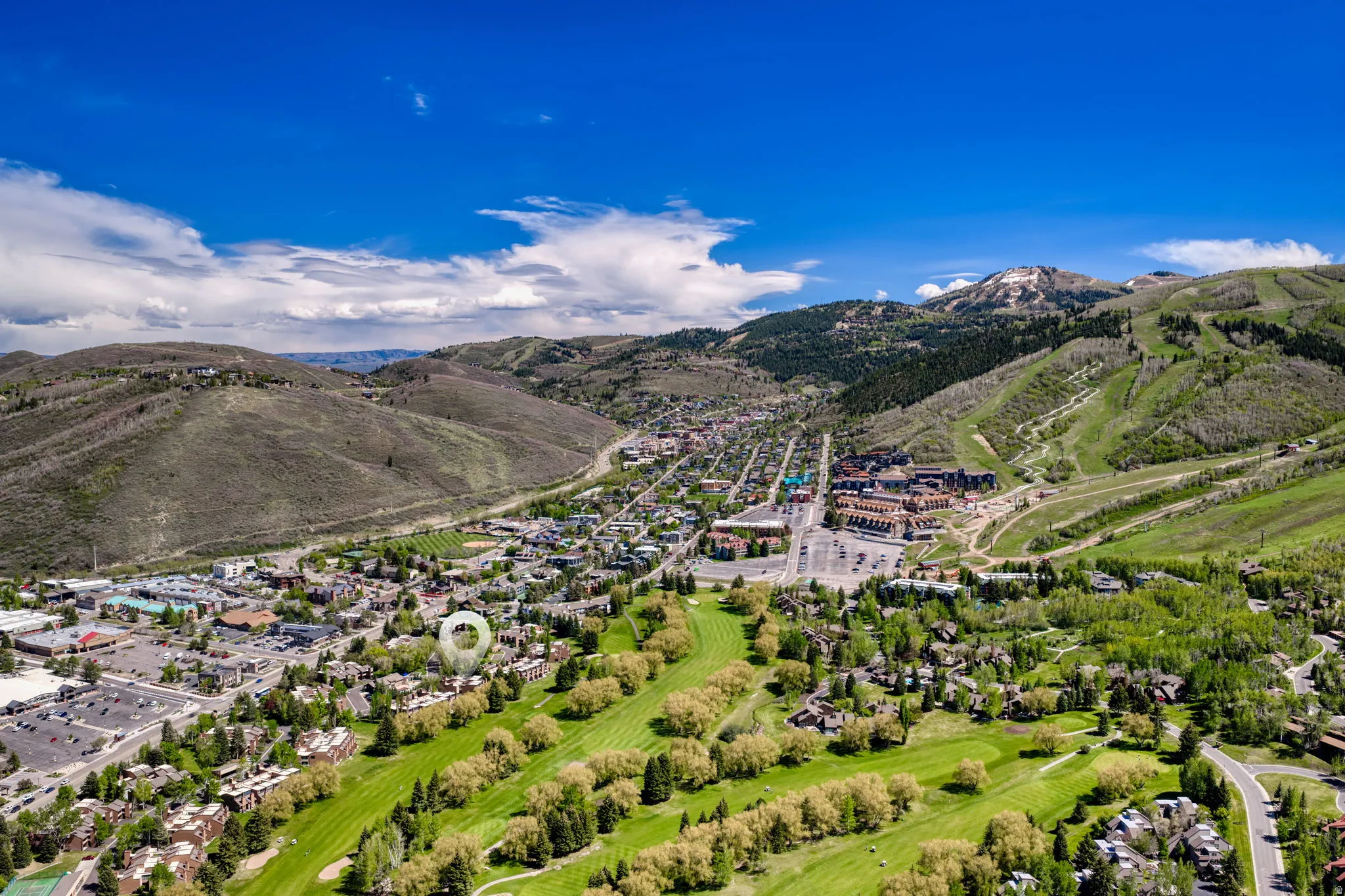 Aerial perspective showcasing a community situated amidst mountainous terrain with a golf course
