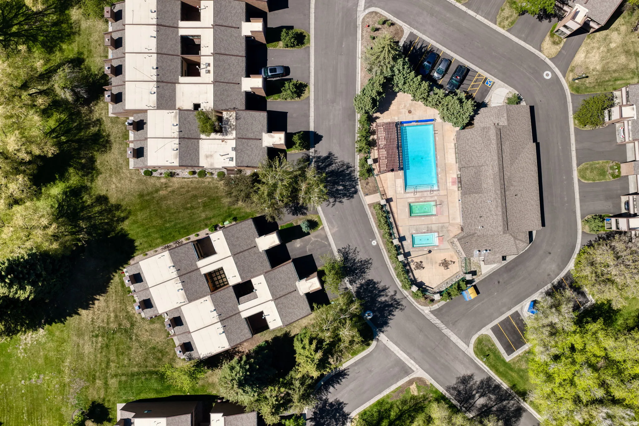 Community amenities featuring a rectangular swimming pool, two smaller pools, and a surrounding paved patio area