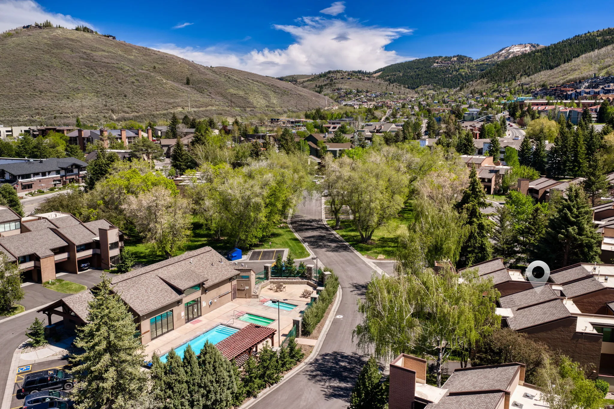 Community amenities featuring an outdoor swimming pool, hot tubs, and a clubhouse building