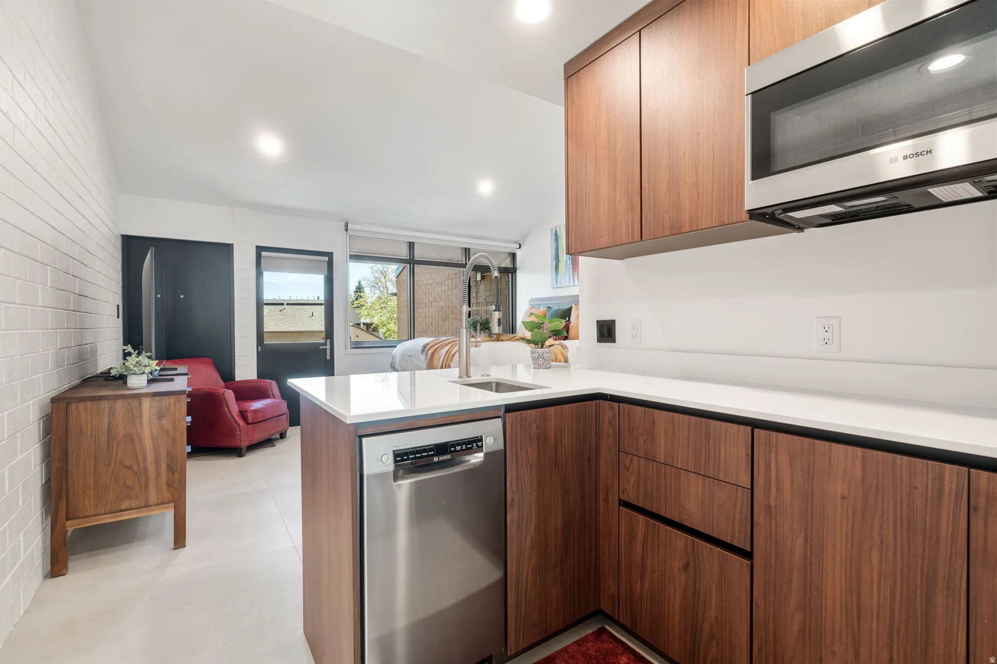 Kitchenette featuring wood-finish cabinetry, white countertops, and stainless steel appliances including a dishwasher and microwave